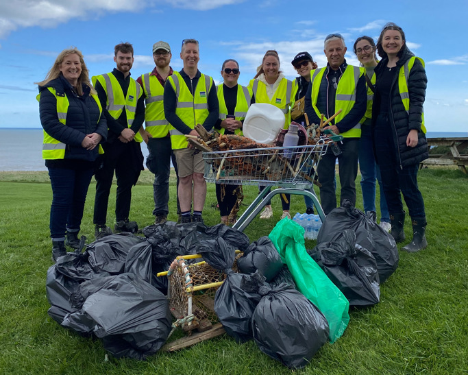 Colleagues from NEPO alongside David Fox from Bunzl Greenham stood behind trolley and bin bags filled with litter collected from Whitburn Beach